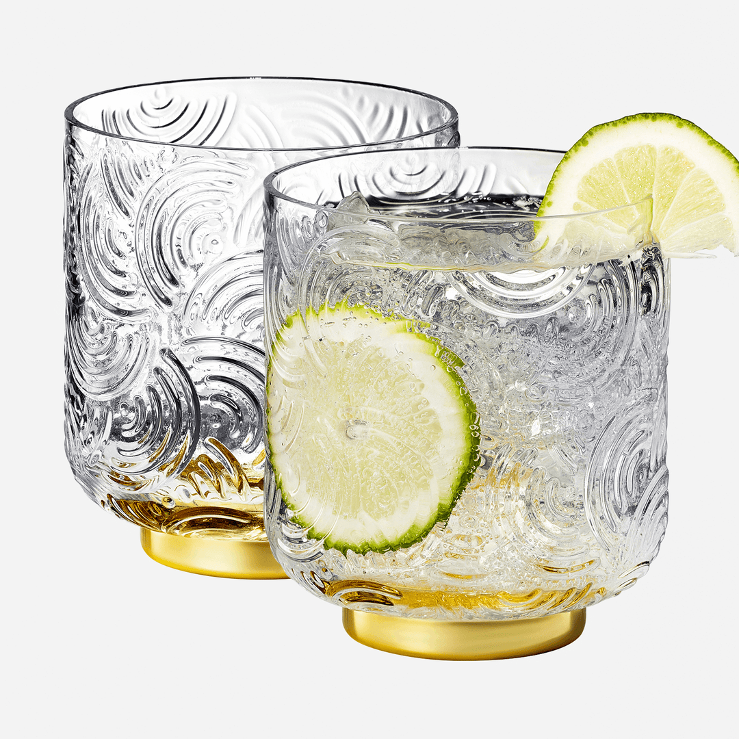 Two glass tumblers with lime slices on a white background