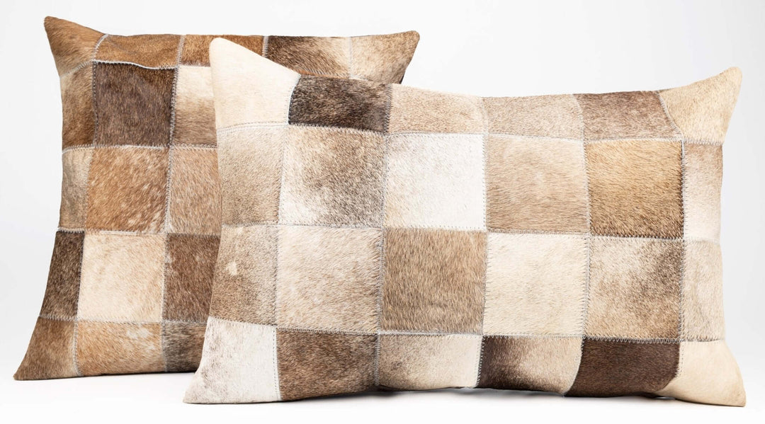 Two patchwork cowhide pillows on a white background