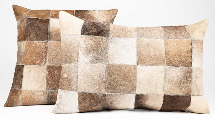 Two patchwork cowhide pillows on a white background