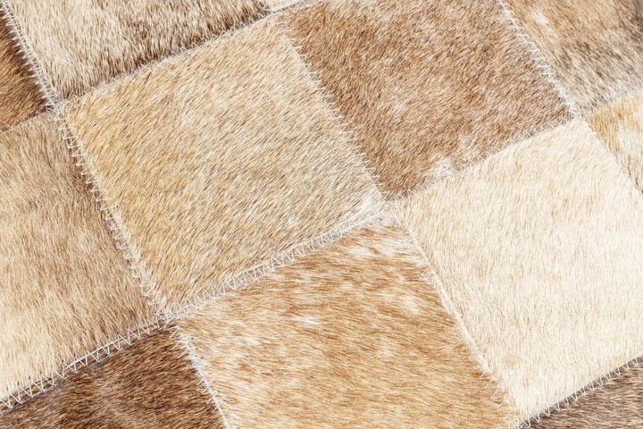 Close-up of a patchwork pillow with brown and beige diamond patterns.