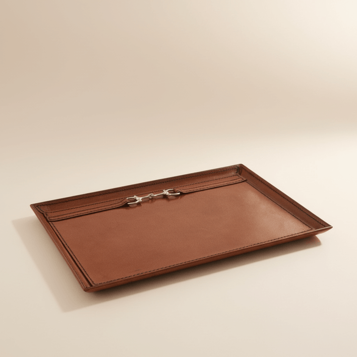 Brown leather tray with a silver clasp on a beige background