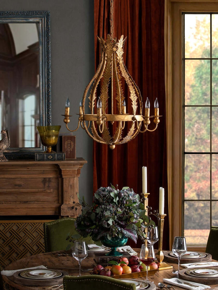 Decorative chandelier hanging above a table set for dinner with autumn-themed decor.