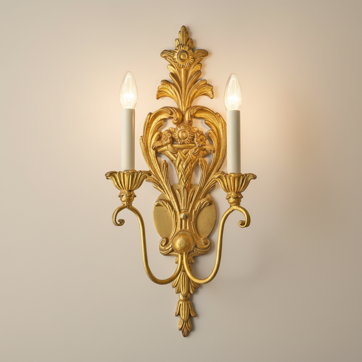 Decorative gold wall sconce with two lit candles on a beige background