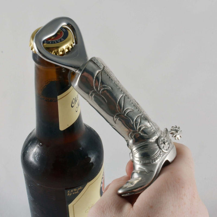 Hand using a decorative bottle opener on a bottle against a plain background