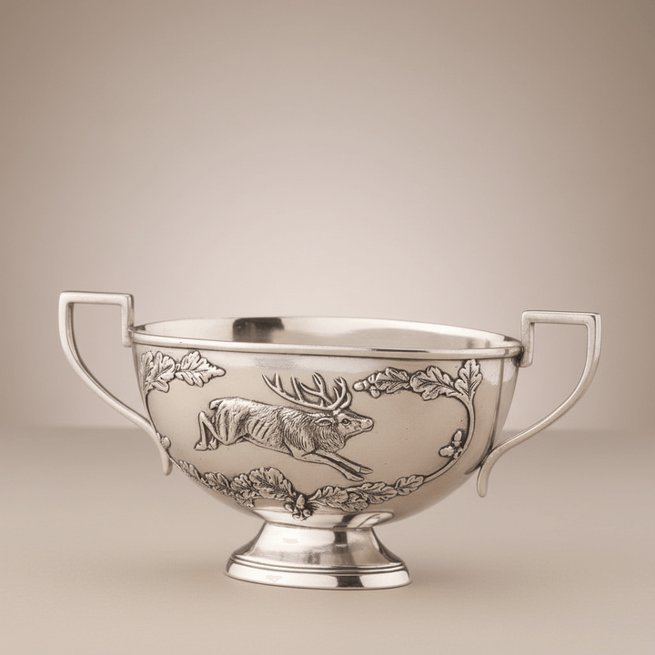 Silver bowl with engraved elk design on a beige background