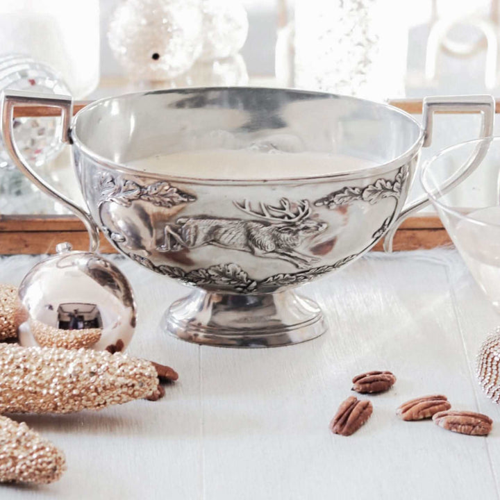 Silver decorative bowl with intricate designs on a white surface with decorative items.