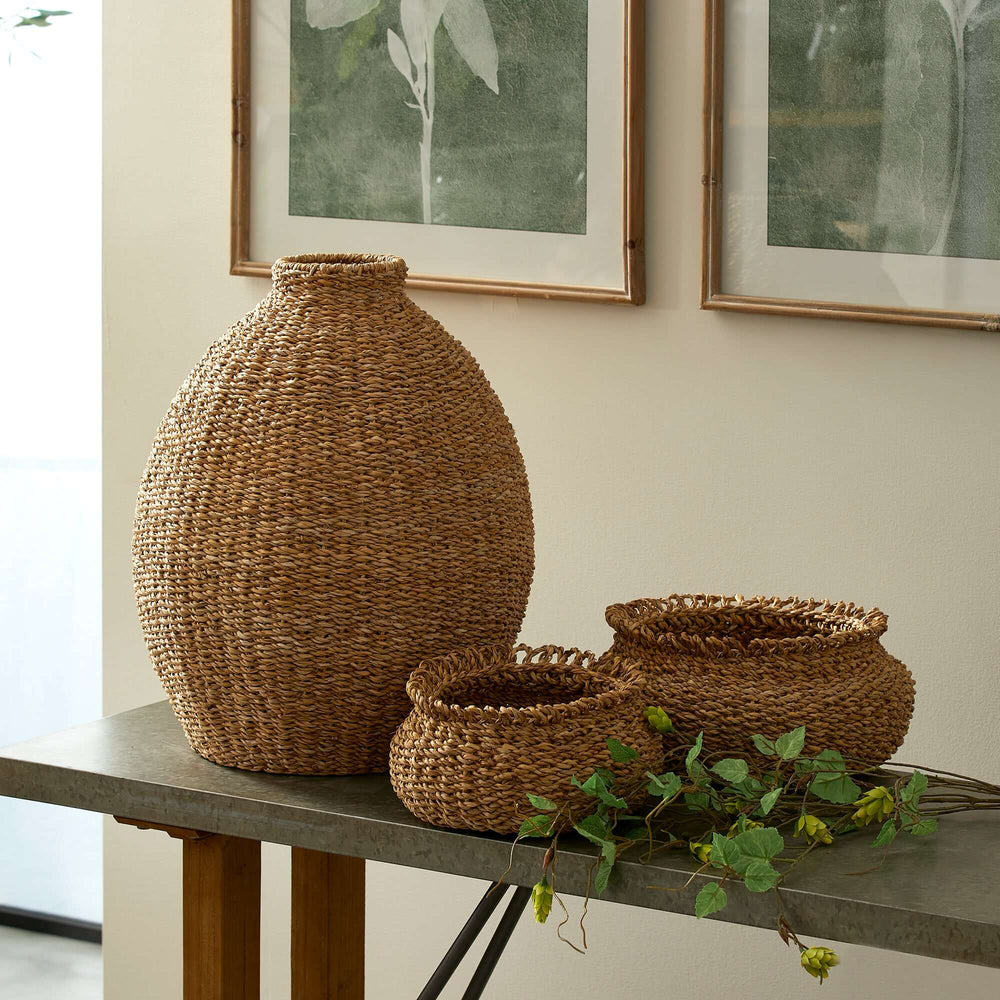 Handwoven Seagrass Teardrop Vase for Boho and Coastal Decor. placed on console table with two other woven baskets.