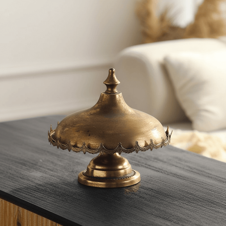Decorative gold metal cloche on a wooden surface with a blurred background