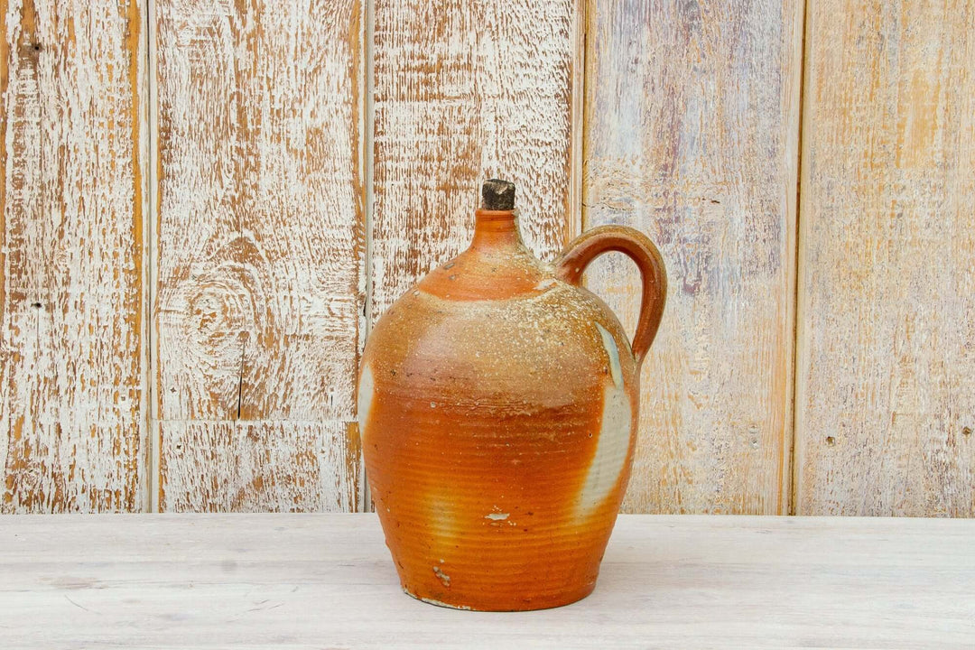 Vintage ceramic jug with a rustic finish on a wooden surface