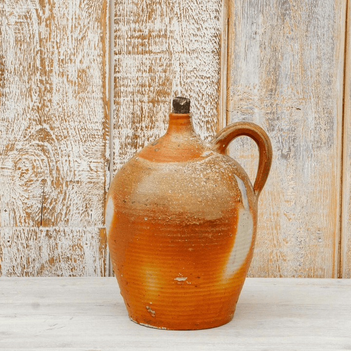 Vintage ceramic pitcher with a rustic finish on a wooden surface