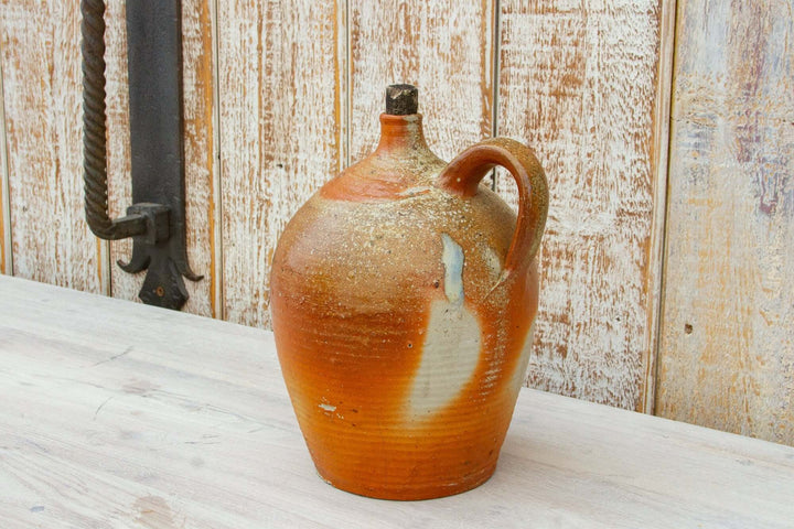 Vintage ceramic jug with brown and beige glaze on a wooden surface.