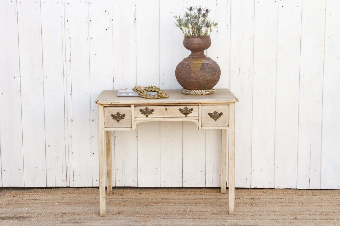 Wooden console table with decorative items against a white paneled wall.