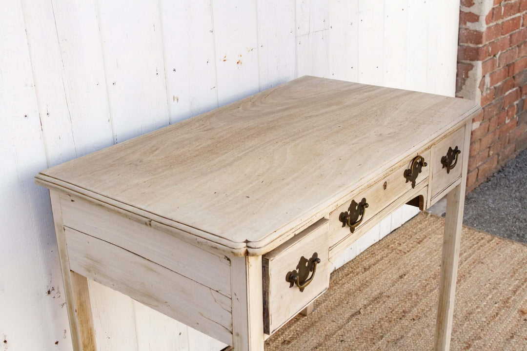 Wooden table with drawers against a white wall and brick wall background