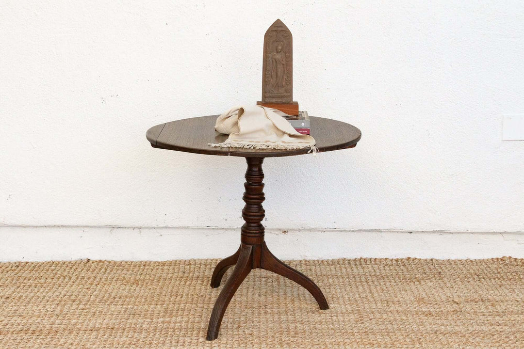 Small round wooden table with a decorative item on a white wall background