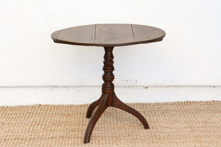 Round wooden table with a pedestal base on a white wall background