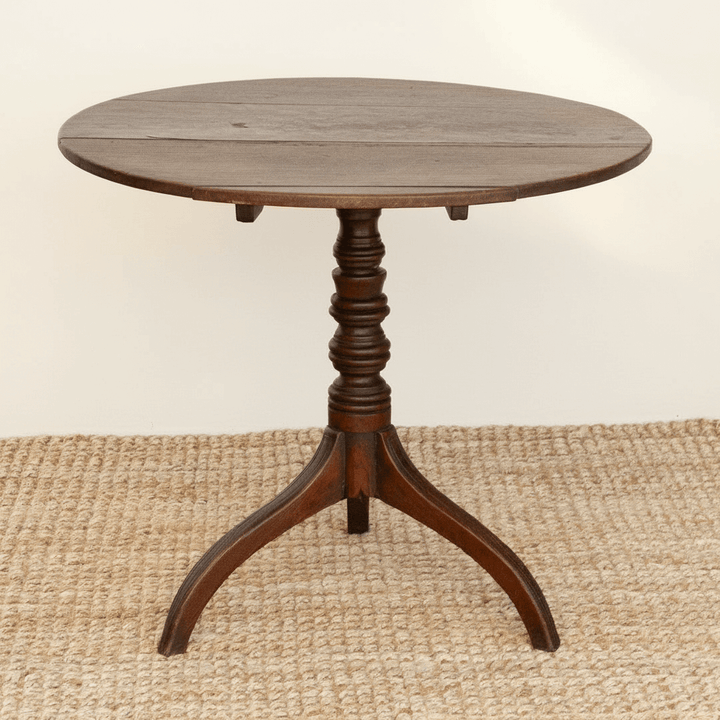 Round wooden table with a pedestal base on a beige rug