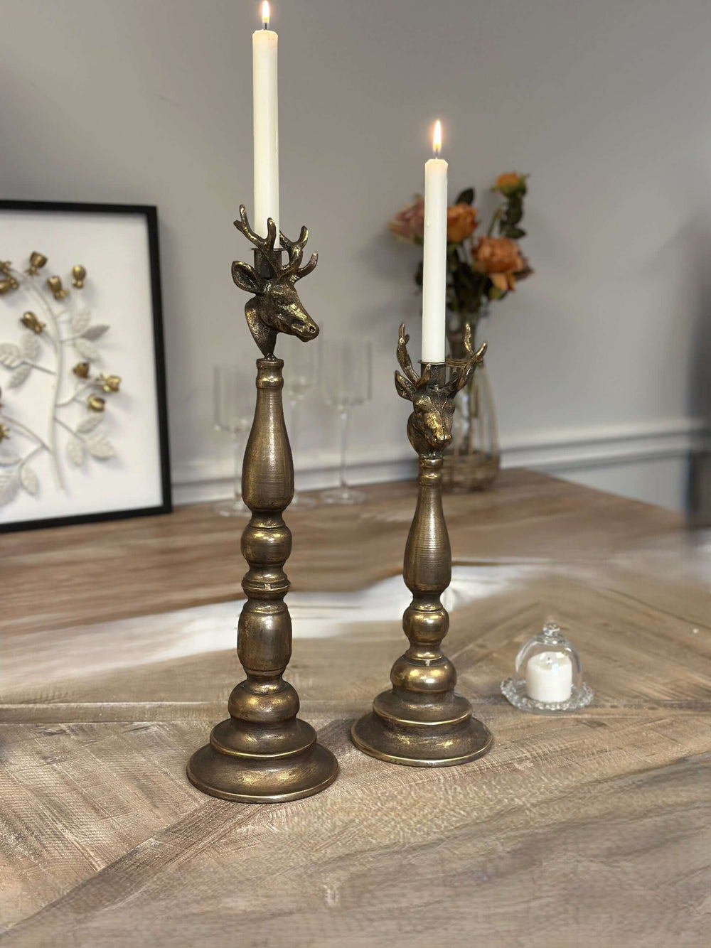 Vintage brass deer head candle holders with elegant antlers on a wooden table, showcasing antique beauty and rustic charm.
