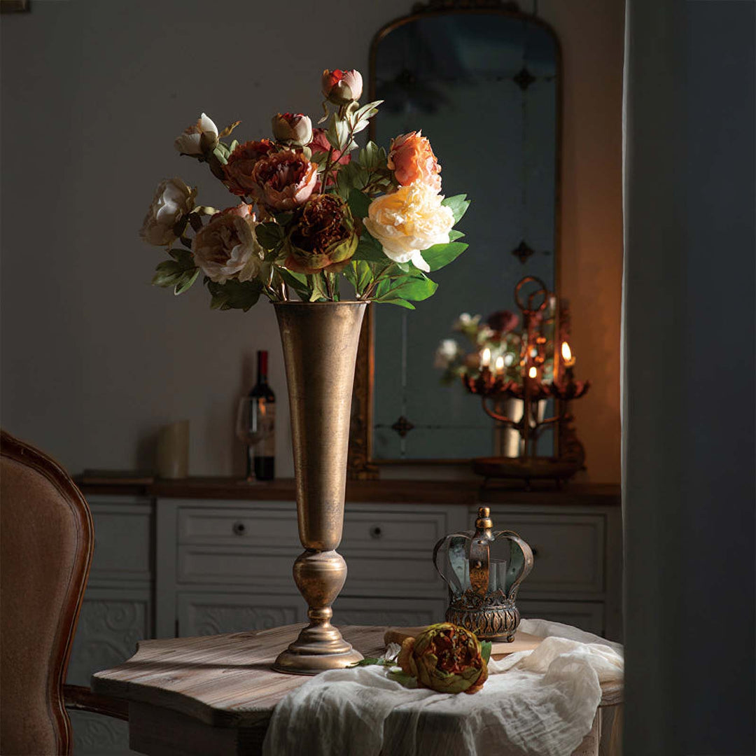Vintage tall gold trumpet vase with floral arrangement in elegant setting