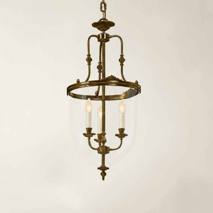 Bronze pendant light fixture with three candles on a plain background