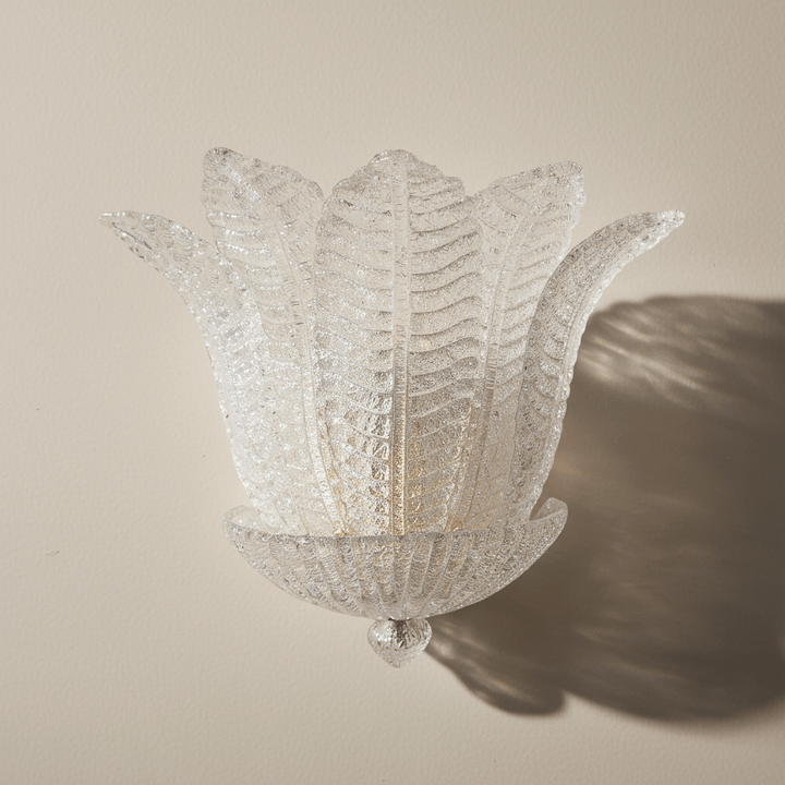 Decorative wall light fixture with a floral design on a beige wall.