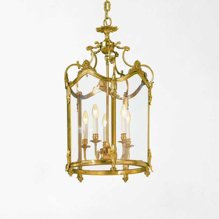 Decorative brass pendant light with clear glass on a white background