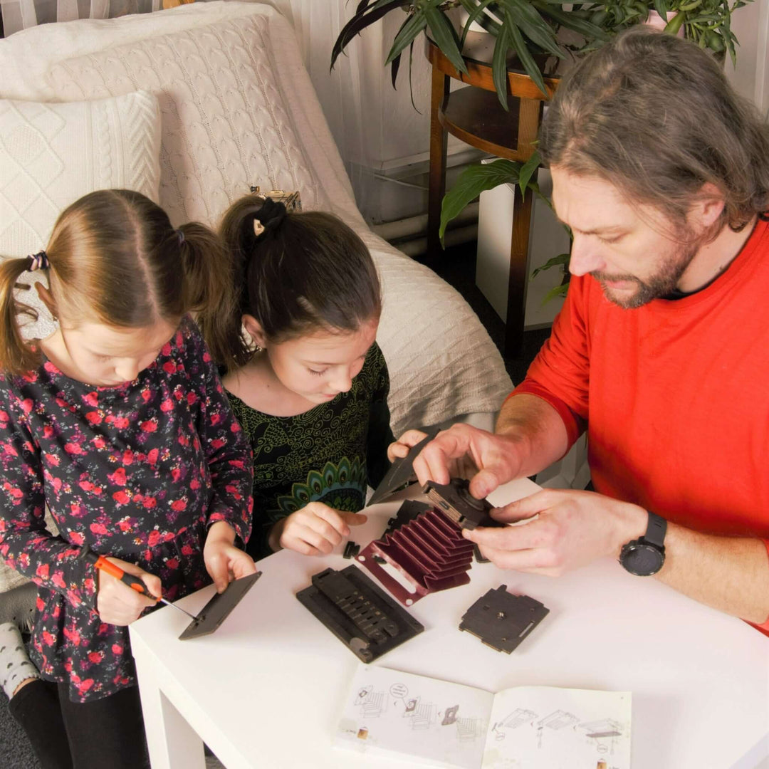 Family assembling Pinhole Square Instant Film Camera DIY Kit at home, engaging in a vintage-inspired photography project together.