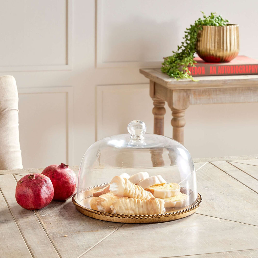 Large Vintage Glass Cloche with Gold Braided Tray on a kitchen table with food inside it.