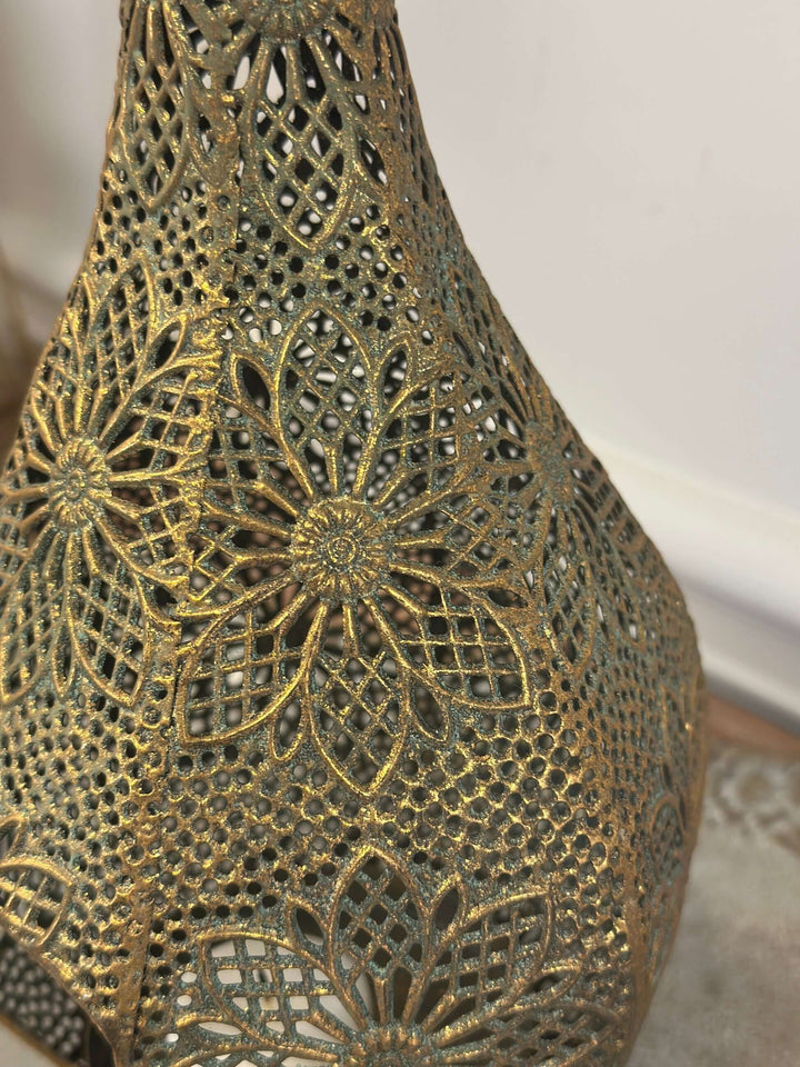 Vintage brass teardrop lantern with floral filigree detailing evokes old-world charm and elegance, ideal for adding romantic candlelight ambiance.