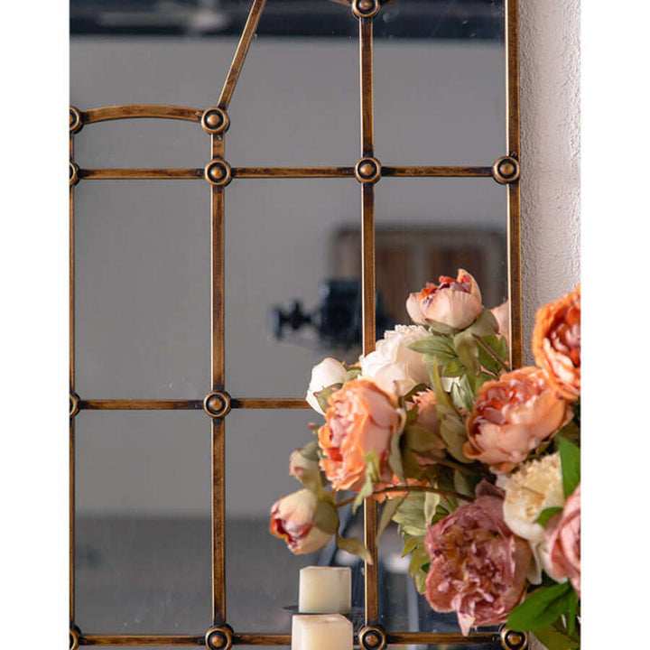 Antique arched wall mirror with metal grid frame and flowers, adding European elegance and vintage charm to home decor.