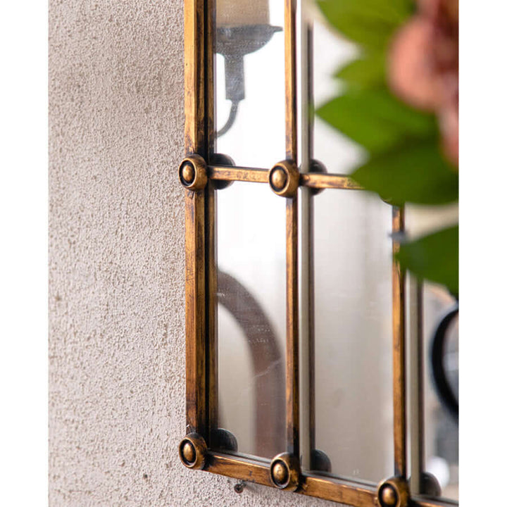 Close-up of an antique arched windowpane mirror with a metal grid frame, showcasing elegant craftsmanship and vintage design.
