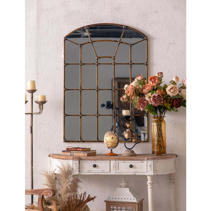 Antique Arched Windowpane Wall Mirror with Metal Grid Frame on vintage console table, surrounded by elegant decor in cozy room.