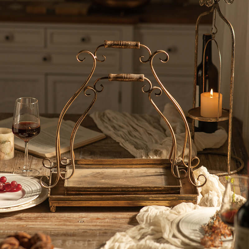 Vintage-inspired antique gold metal serving tray set with ornate handles on a rustic farmhouse table, surrounded by festive decor.