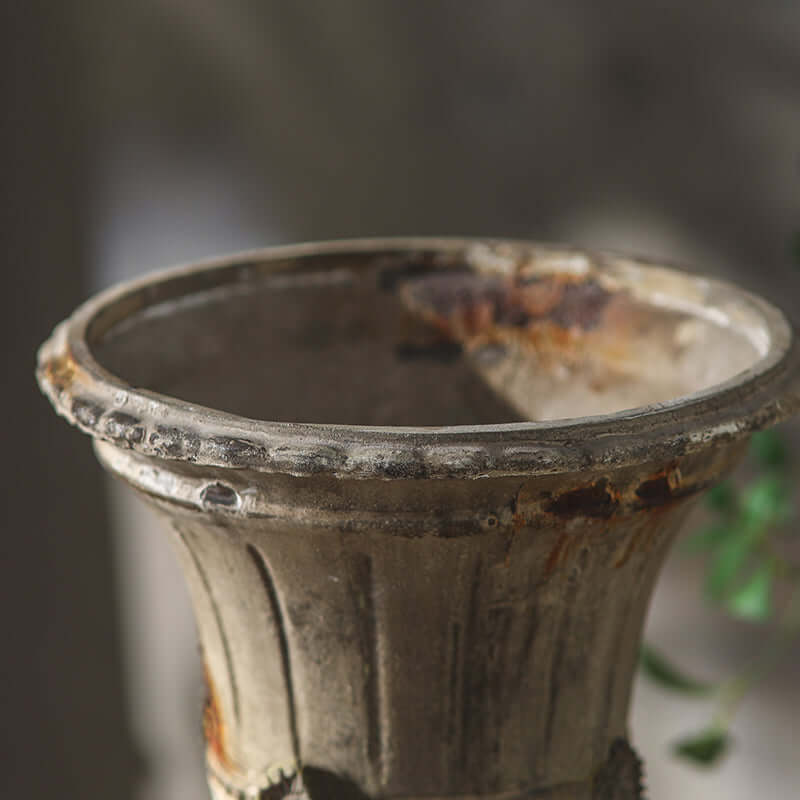 Rust-colored metal vase with a blurred background