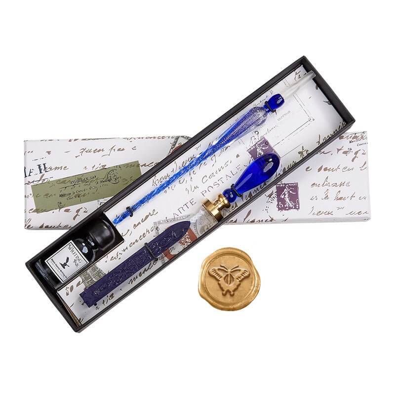 Wand with blue accents, ink bottles, and a wax seal in a decorative box on a white background