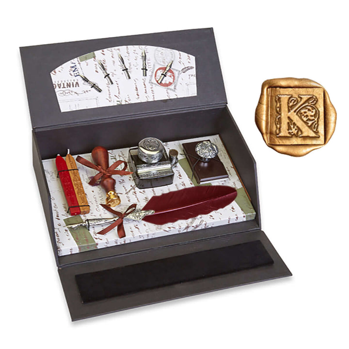 Stationery set with inkwell, quill, and wax seal in a black box on a white background