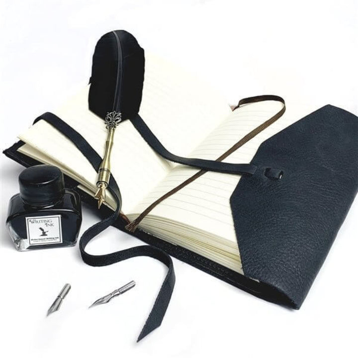 Feather pen, ink bottle, and notebook on a white background