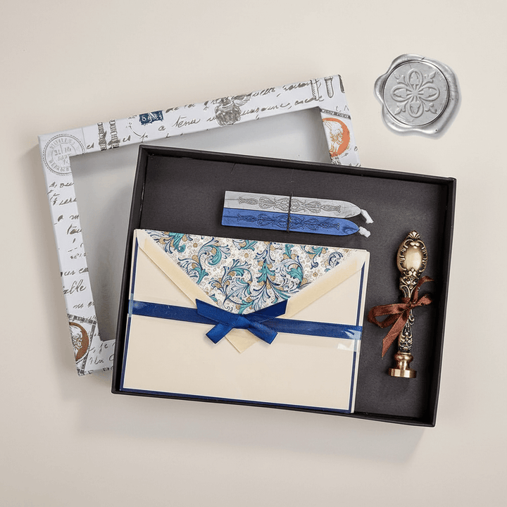 Stationery set with envelopes, a sealing wax stamp, and a sealing wax in a black box on a white background.