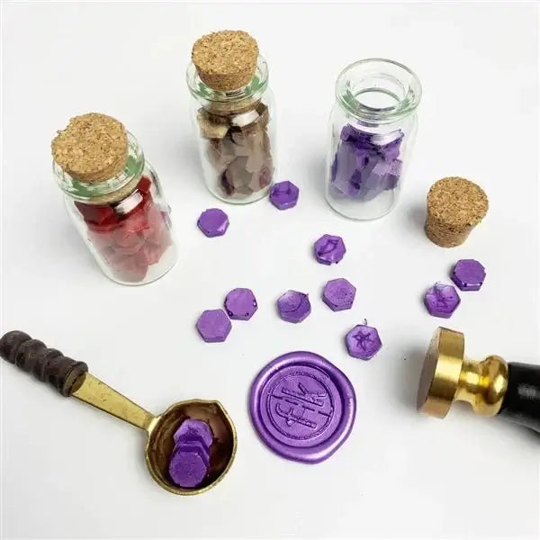 Glass jars with cork lids, purple wax seals, and a gold stamp on a white background