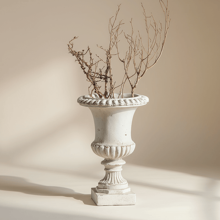 Decorative white urn with dried branches against a beige background