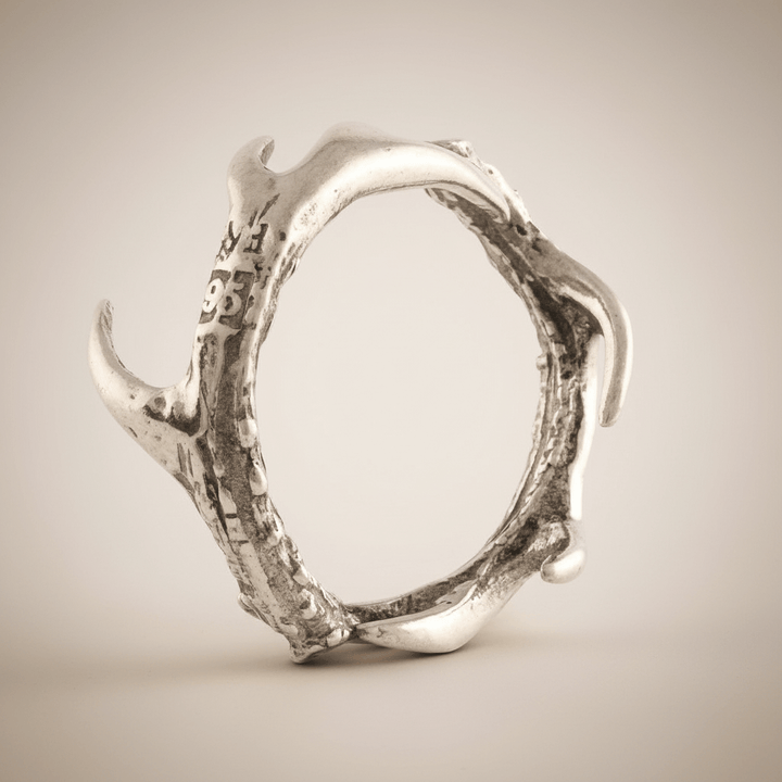 Silver antler-shaped napkin ring on a beige background
