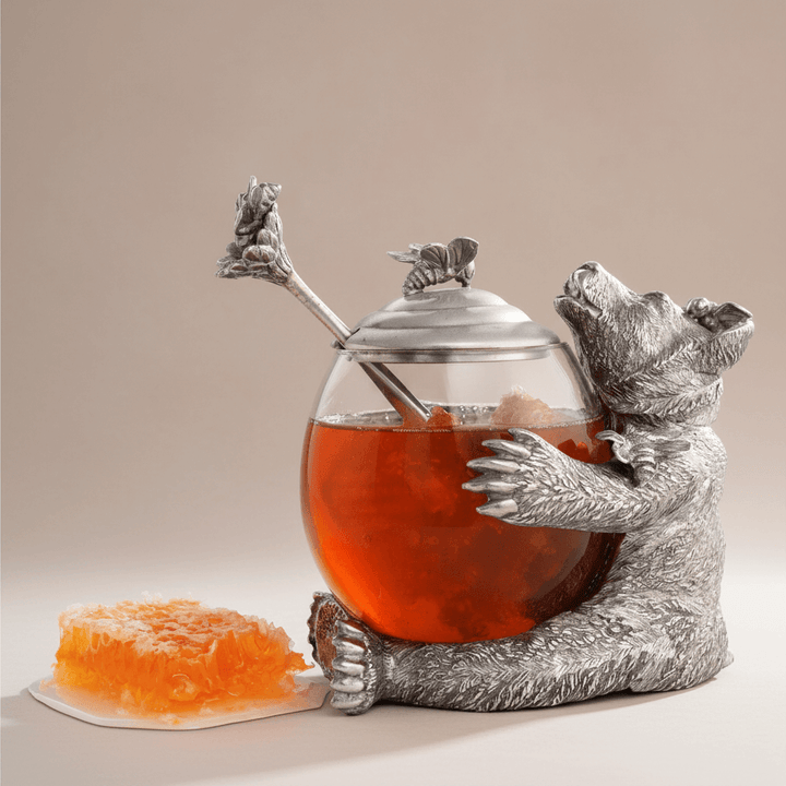 Silver bear-shaped honey jar with honeycomb on a beige background