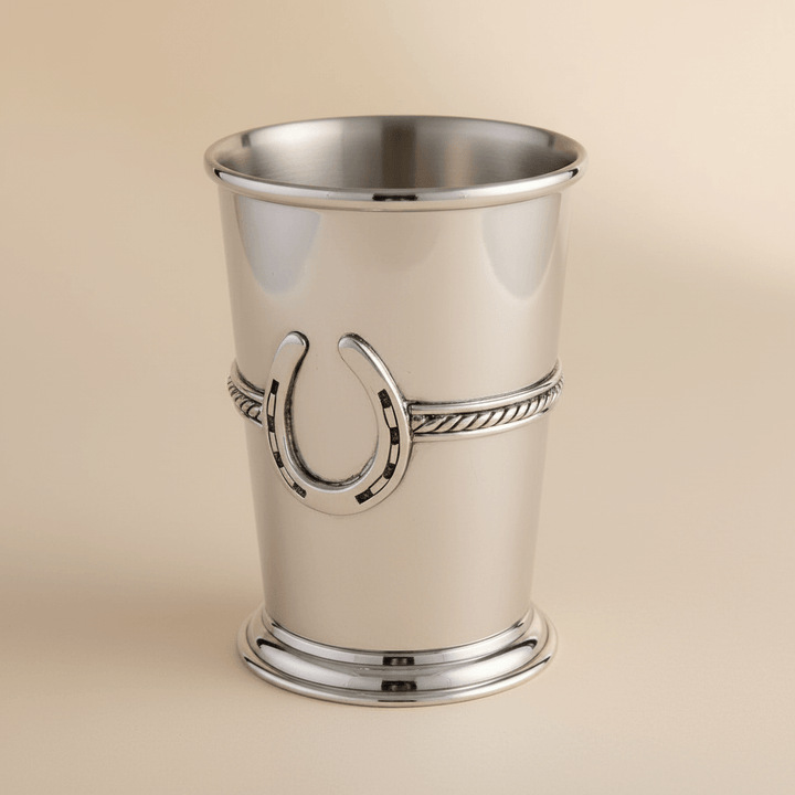 Silver mint julep cup with a horseshoe design on a beige background