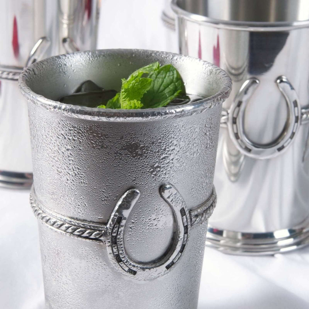 Silver mint julep cup with horse shoe design on a white background