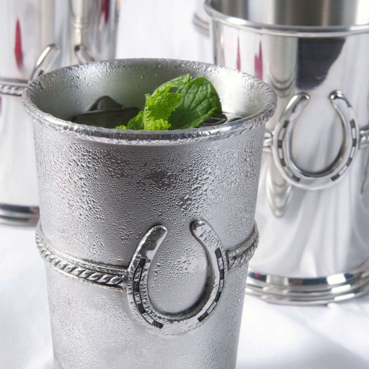 Silver mint julep cup with horse shoe design on a white background