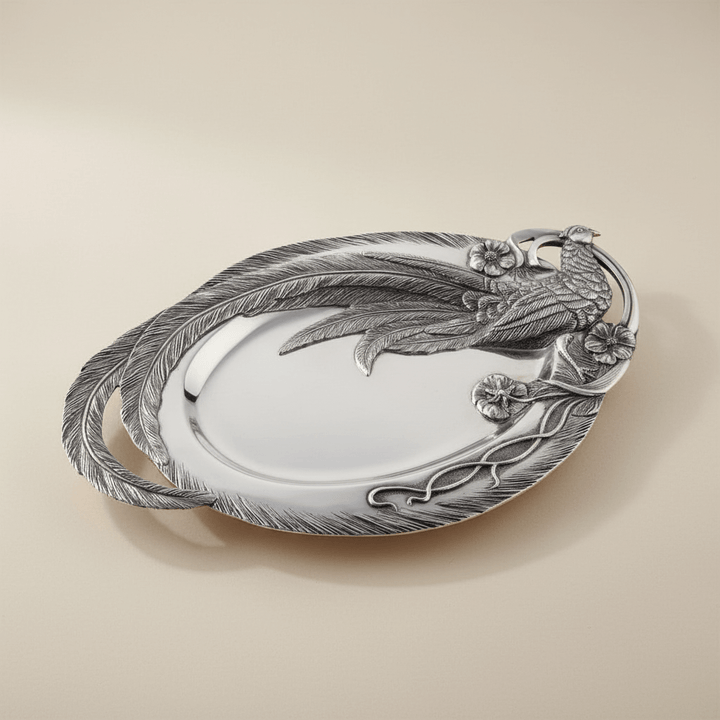 Decorative silver platter with a pheasant, feather and floral designs on a beige background