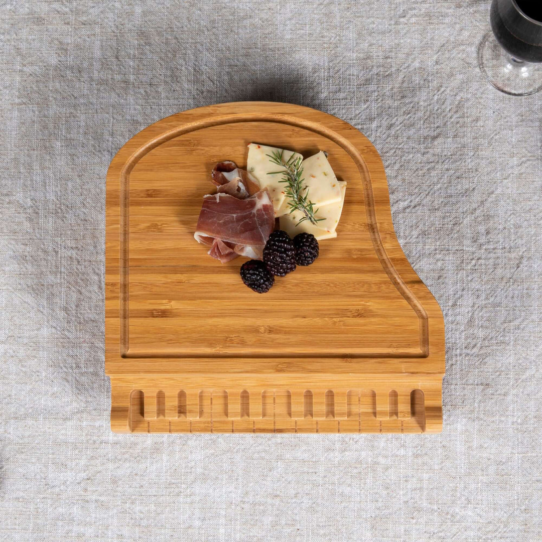 Top view of Piano Cheese Board and Knife Set with cheese and fruits, made of bamboo shaped like a grand piano.