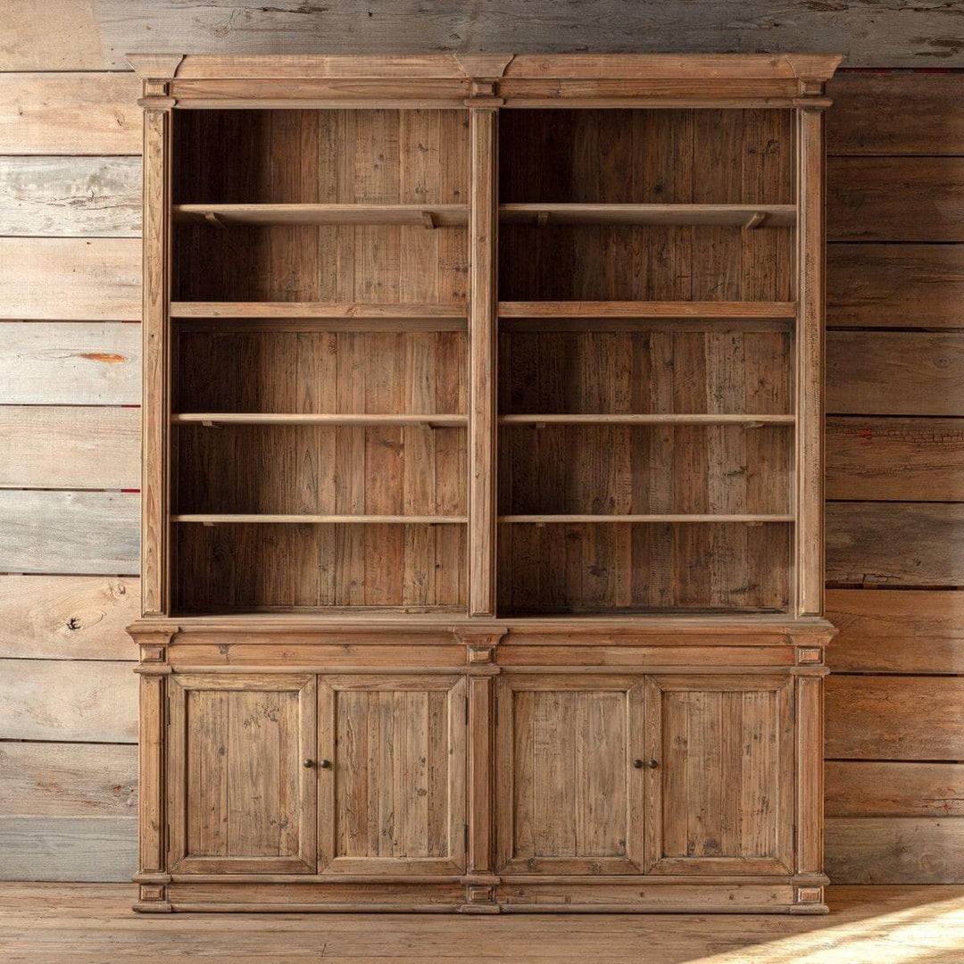 Large wooden bookshelf with open shelves and closed doors against a wooden wall.