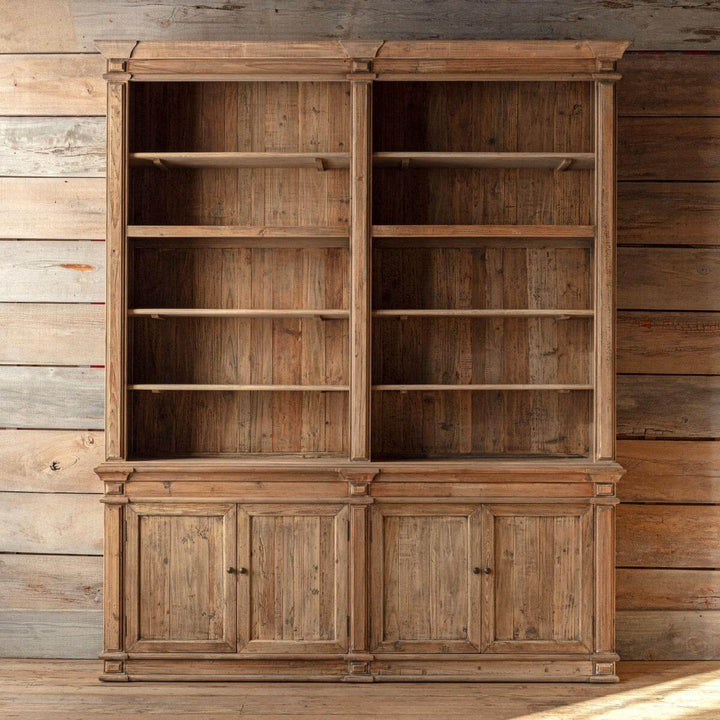 Large wooden bookshelf with open shelves and closed doors against a wooden wall.