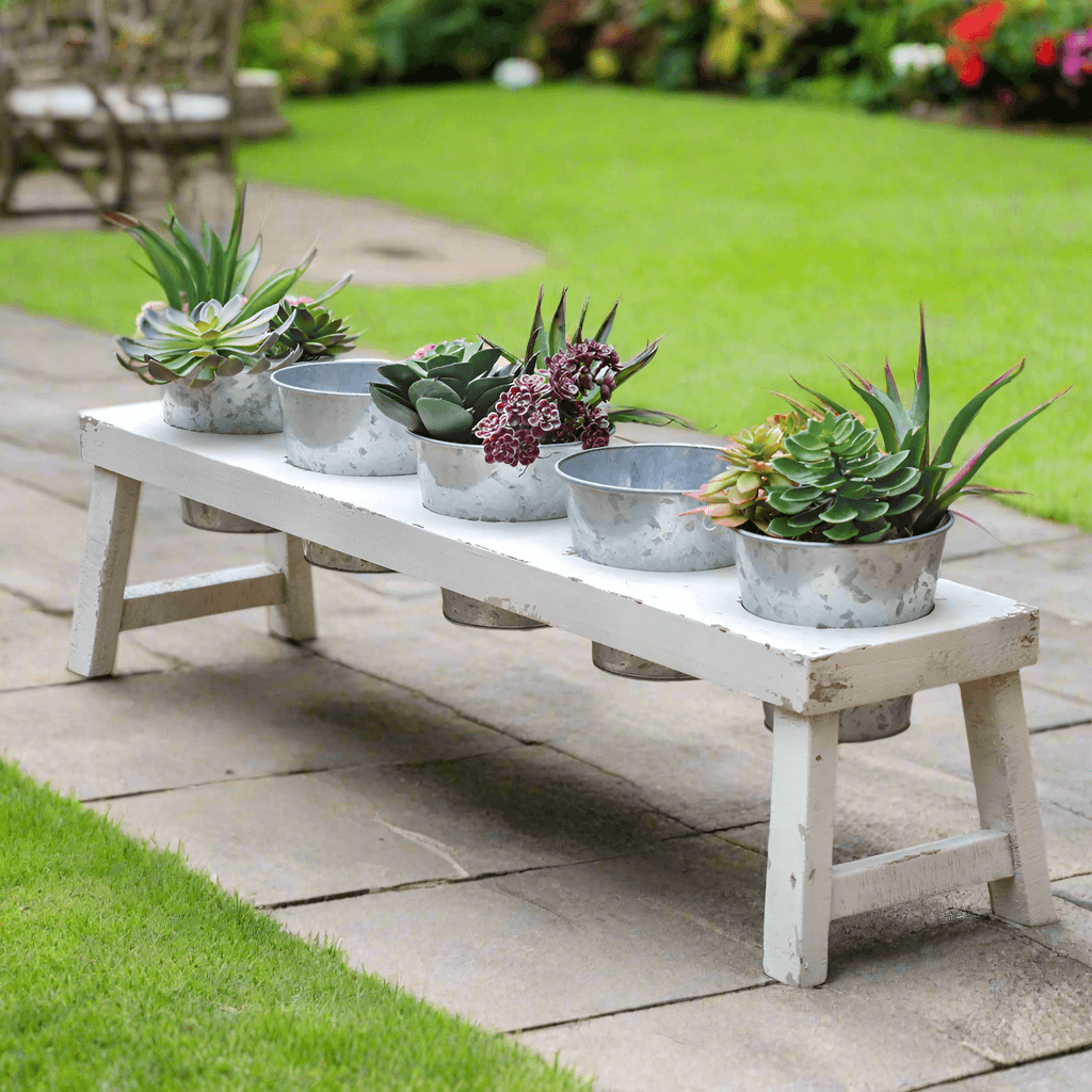 Rustic farmhouse bench planter with galvanized pots displaying succulents in outdoor garden setting.