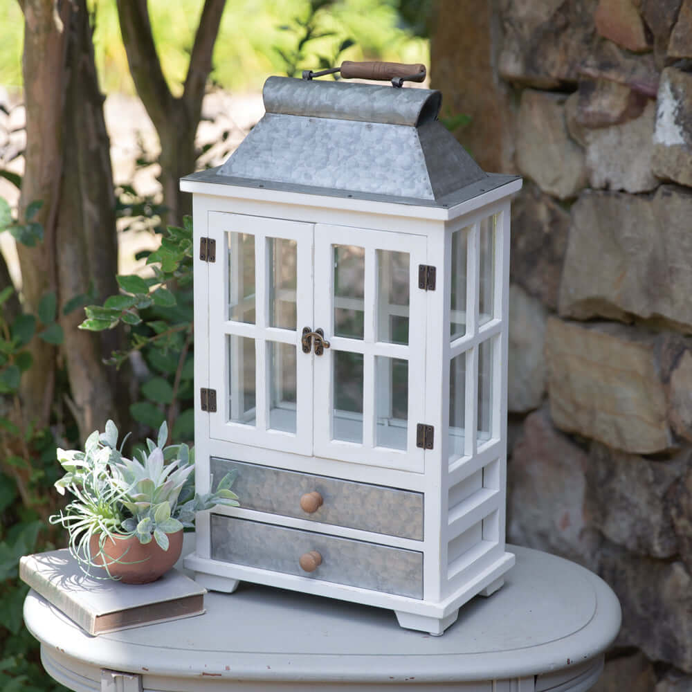 Rustic farmhouse greenhouse lantern with drawers, whitewashed wood, and galvanized metal roof, perfect for home décor.